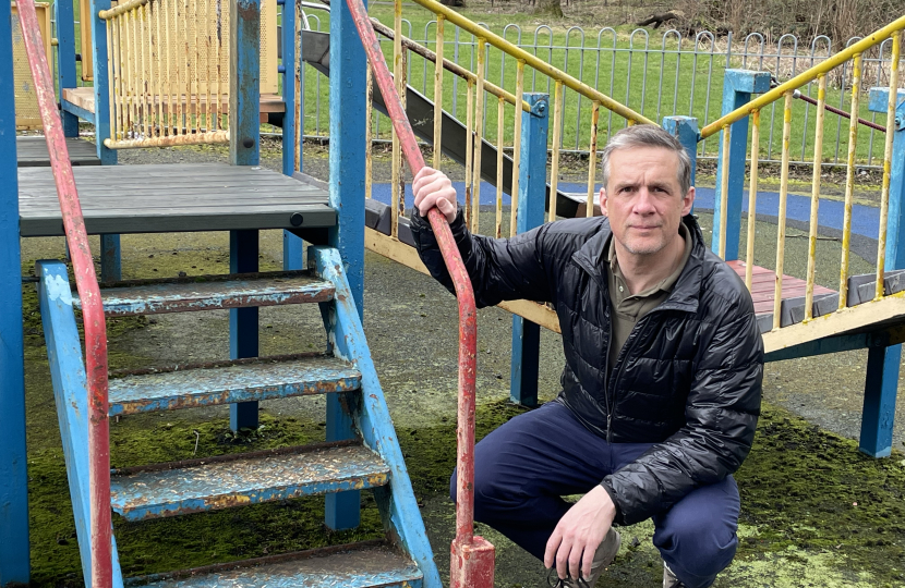 Christopher is posing in a playground next to steps that need to be repainted.