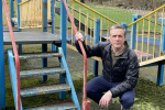 Christopher is posing in a playground next to steps that need to be repainted.