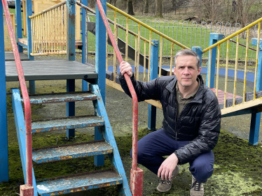 Christopher is posing in a playground next to steps that need to be repainted.