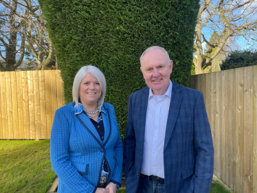 Sue and Graeme pose outside in front of a tree.